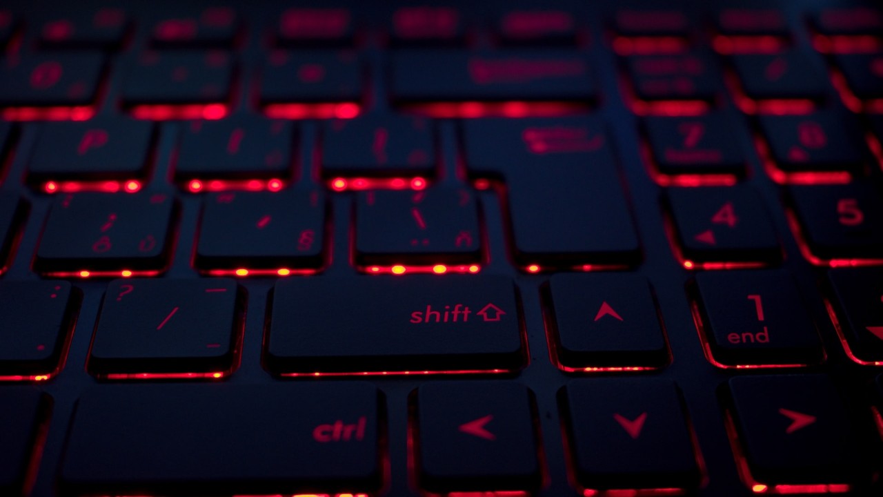 close up of black keyboard with red light shining through the keys